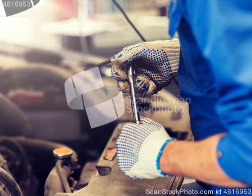 Image of mechanic man with wrench repairing car at workshop