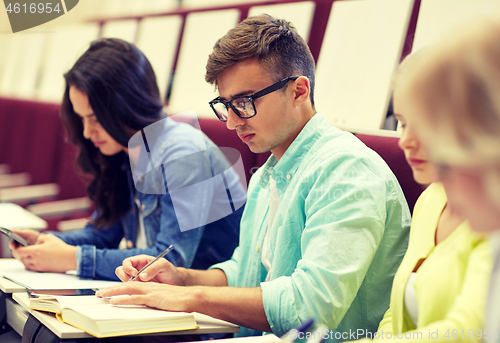 Image of group of students with books writing at lecture