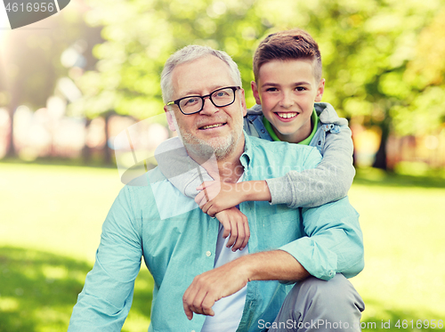 Image of grandfather and grandson hugging at summer park