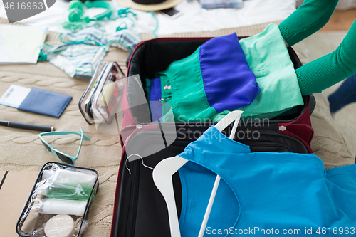 Image of woman packing travel bag at home or hotel room