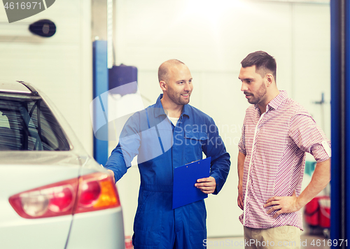 Image of auto mechanic with clipboard and man at car shop