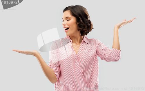 Image of young woman in striped shirt holding something