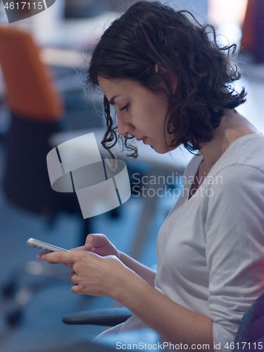 Image of Businesswoman typing on phone  in office