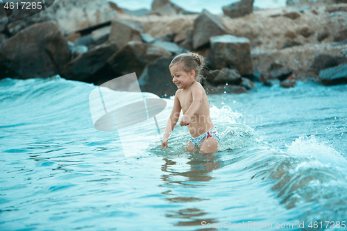 Image of The happy little girl playing on the beach at the day time