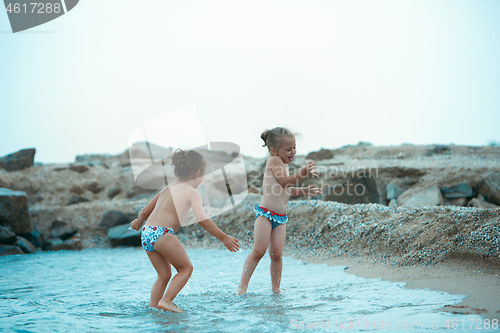 Image of Two happy children playing on the beach at the day time