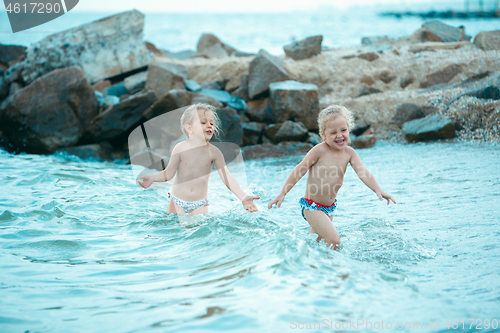 Image of Two happy children playing on the beach at the day time