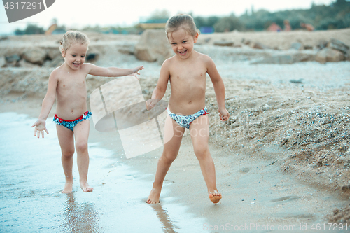 Image of Two happy children playing on the beach at the day time