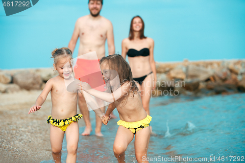 Image of Happy family enjoying walk on the beach