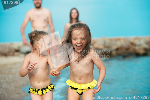 Image of Happy family enjoying walk on the beach