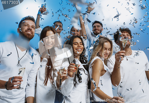 Image of Group of cheerful joyful young people standing and celebrating together over blue background