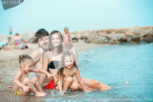 Image of Happy family enjoying walk on the beach