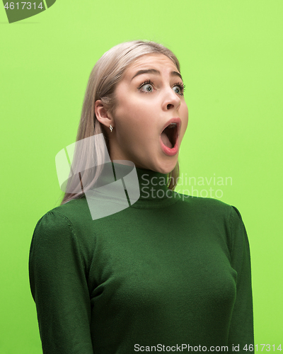 Image of The woman screaming with open mouth isolated on green background, concept face emotion