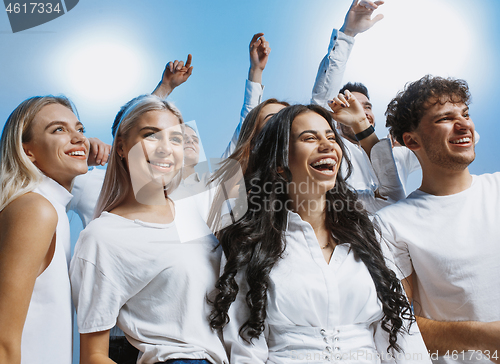 Image of Group of cheerful joyful young people standing and celebrating together over blue background