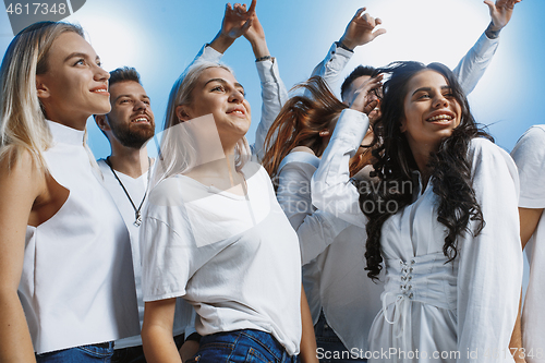 Image of Group of cheerful joyful young people standing and celebrating together over blue background