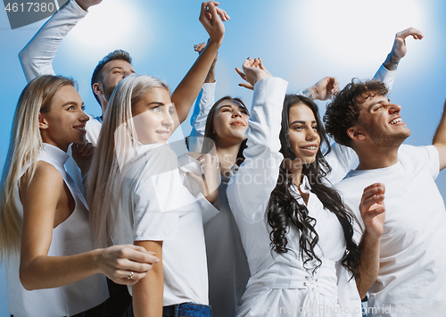 Image of Group of cheerful joyful young people standing and celebrating together over blue background