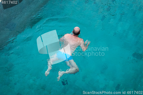 Image of Balding man swimming in clean blue water