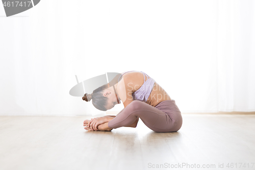 Image of Portrait of gorgeous active sporty young woman practicing yoga in studio. Beautiful girl practice Dandayamana Bibhaktapada Paschimotthanasana, standing separate leg stretching pose