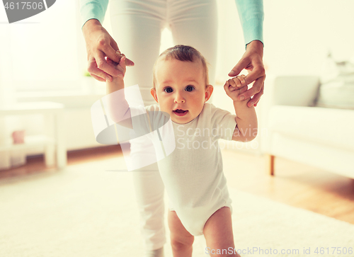 Image of happy baby learning to walk with mother help