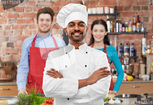 Image of happy male indian chef in toque at cooking class