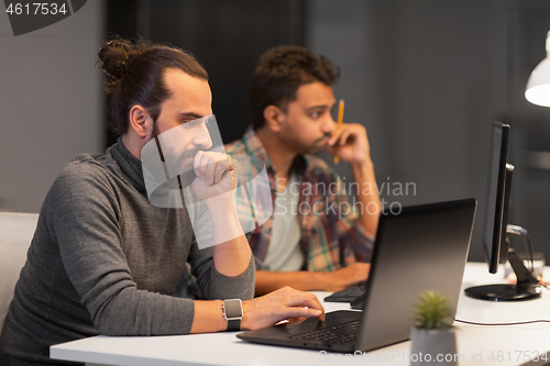 Image of creative team with computer working late at office