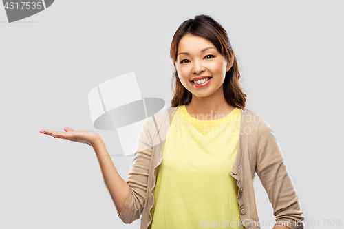 Image of happy asian woman holding something on hand