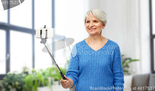 Image of smiling senior woman taking selfie by smartphone