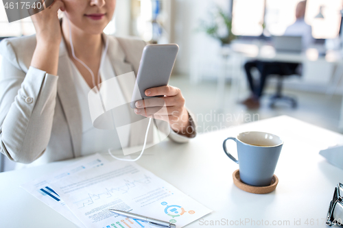 Image of businesswoman with earphones and smartphone