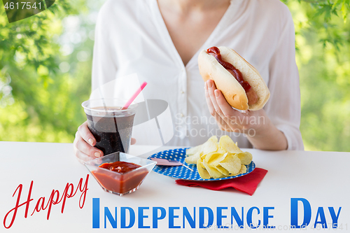 Image of close up of woman eating hot dog with coca cola