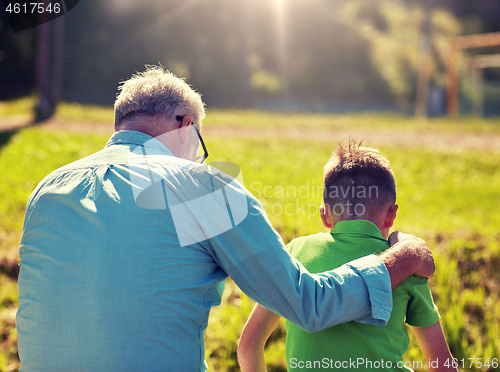 Image of grandfather and grandson hugging outdoors