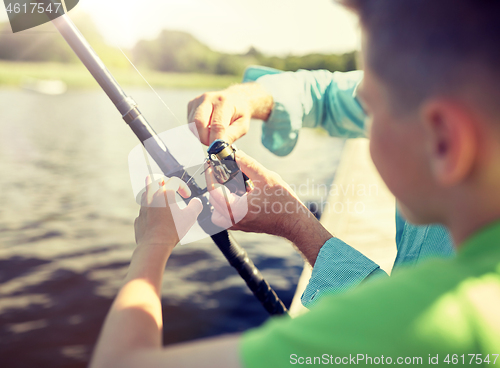 Image of boy and grandfather with fishing rod on river