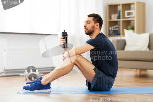 Image of man drinking water during training at home