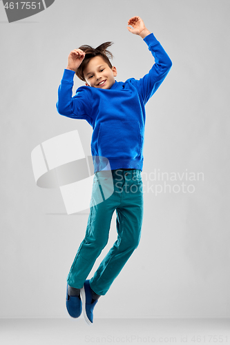 Image of portrait of smiling boy in blue hoodie jumping