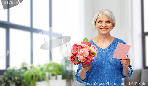 Image of happy senior woman with flowers and greeting card