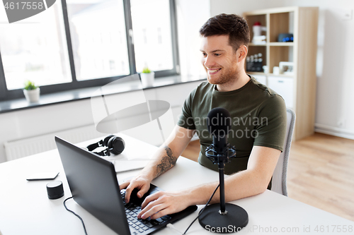 Image of man with laptop and microphone at home office