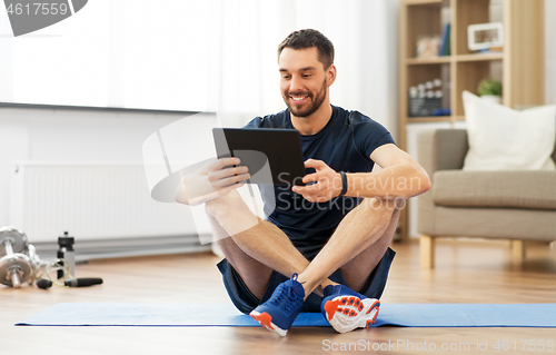 Image of man with tablet computer on exercise mat at home