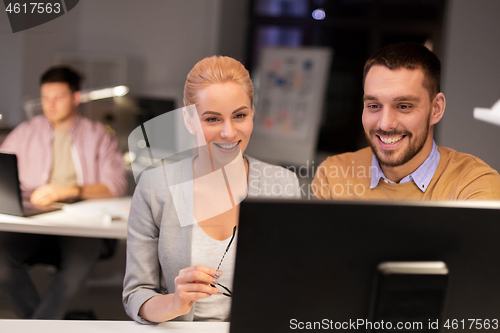 Image of business team with computer working late at office