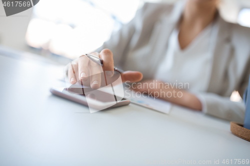 Image of hand of businesswoman using smartphone at office