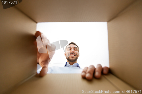 Image of smiling man taking something out of parcel box