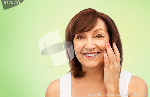 Image of portrait of smiling senior woman touching her face