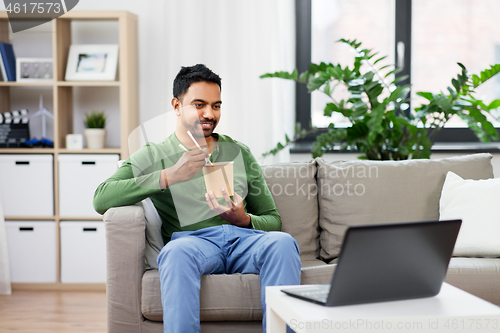 Image of indian man with laptop eating takeout food at home