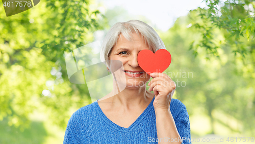 Image of smiling senior woman covering eye with red heart