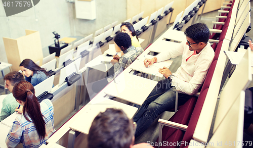 Image of group of students with notebooks in lecture hall