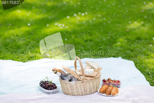 Image of picnic basket, food and wine at summer park