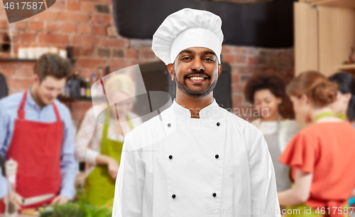 Image of happy male indian chef in toque at cooking class