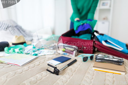 Image of woman packing travel bag at home or hotel room