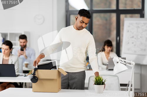 Image of sad fired office worker packing personal stuff