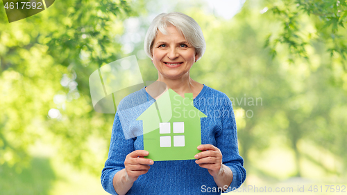 Image of smiling senior woman holding green house icon