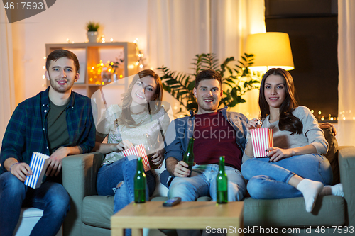 Image of friends with beer and popcorn watching tv at home