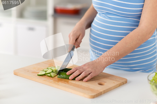 Image of pregnant woman cooking vegetable salad at home