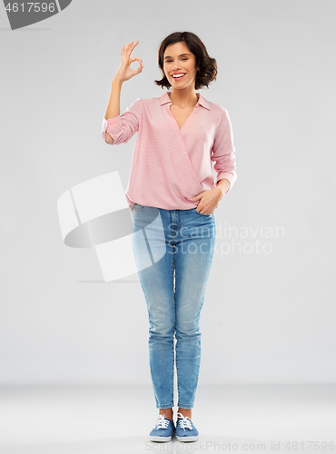 Image of young woman in striped shirt and jeans showing ok